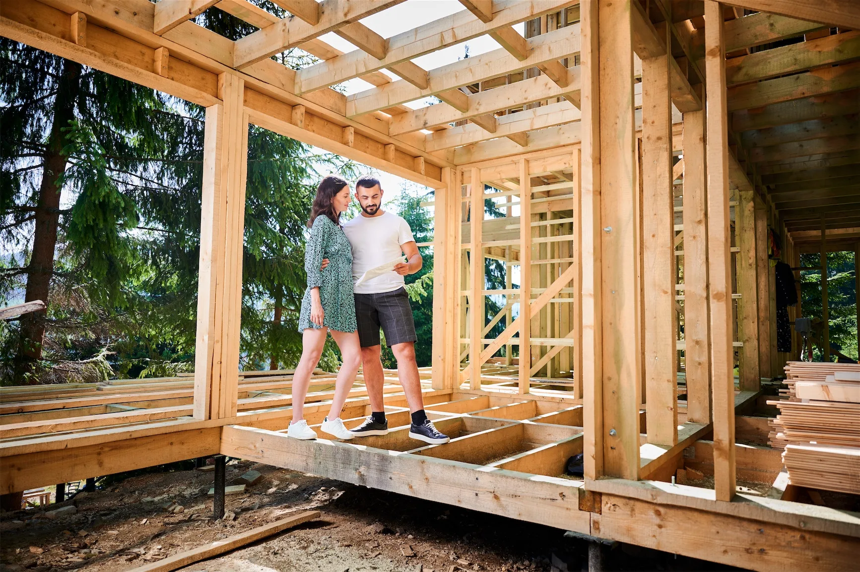 Homeowners reviewing blueprints with a builder inside a home under construction